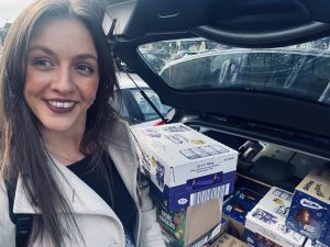 Women smiling in front of car boot filled with Easter eggs