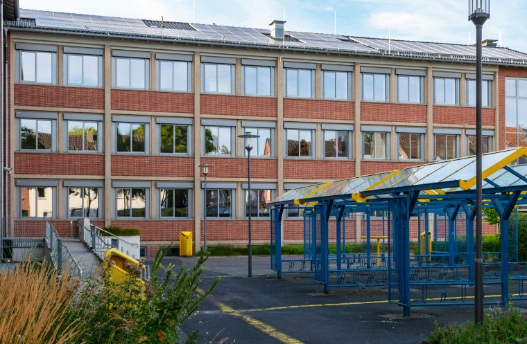 School building with rooftop solar panels, outdoor shelter and grounds